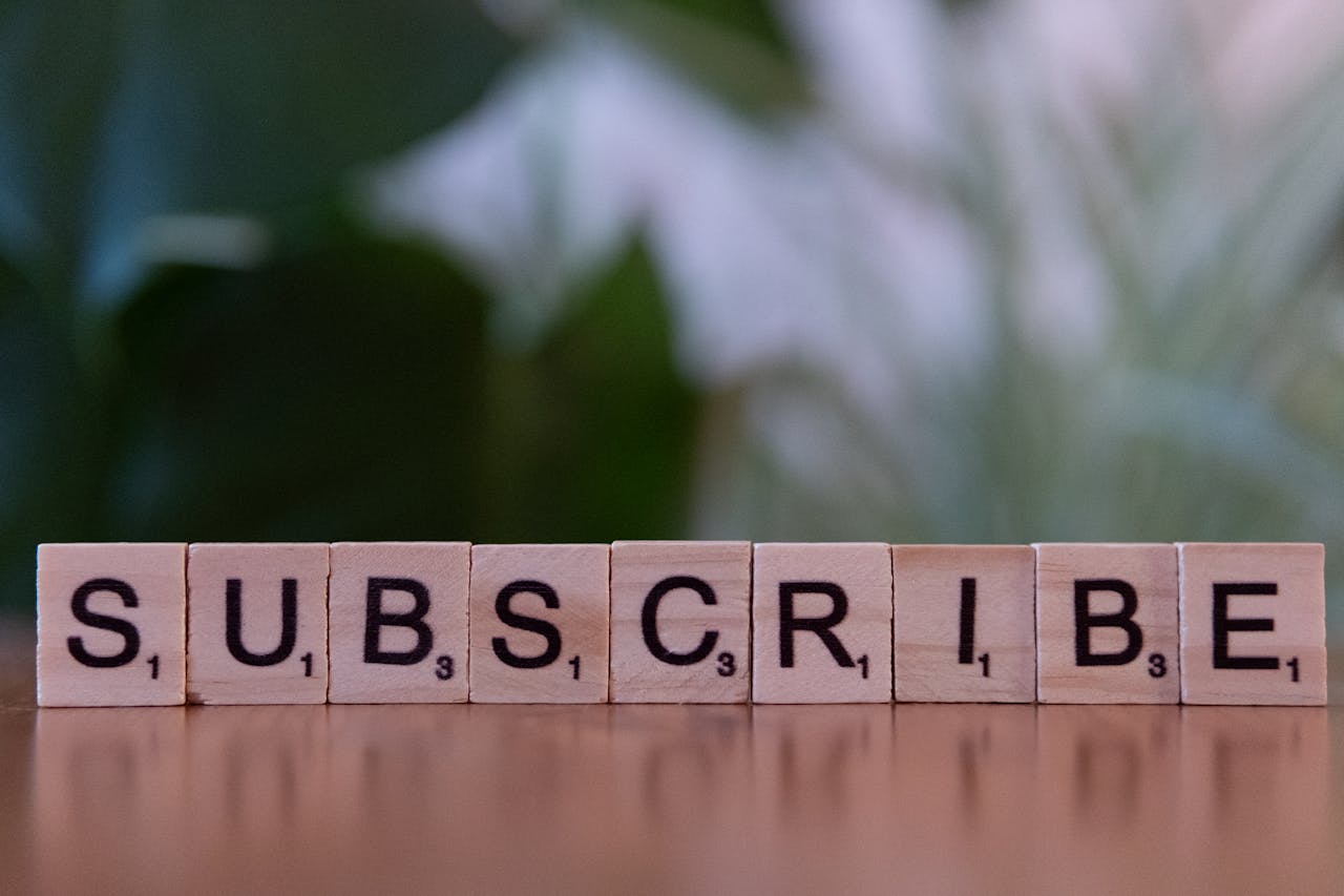 digital-01 Close-up of the word 'SUBSCRIBE' spelled with wooden letter tiles on a table.
